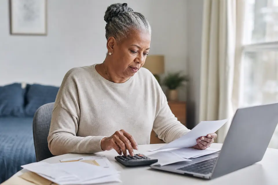 Older woman using a calculator to review an account statement at home